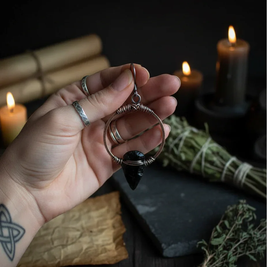 Black obsidian arrowhead earrings on copper hoops - Hand holding for scale