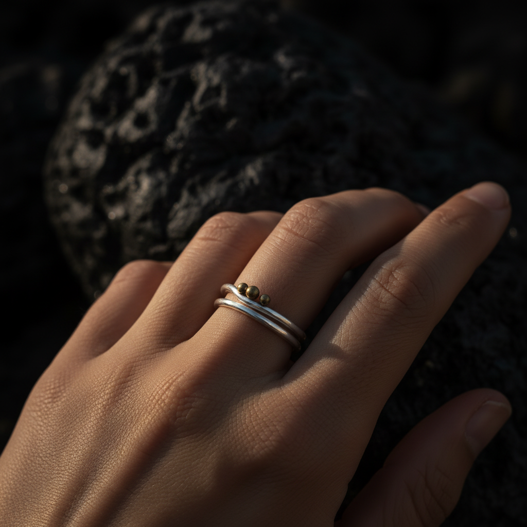 Close-up of Trinity Moon double band ring worn against dark volcanic stone