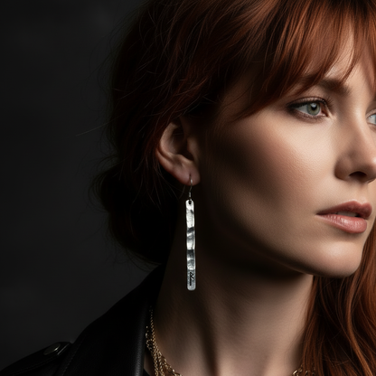 Close-up ear detail of long hammered sterling silver rune bar dangle earring on redheaded model